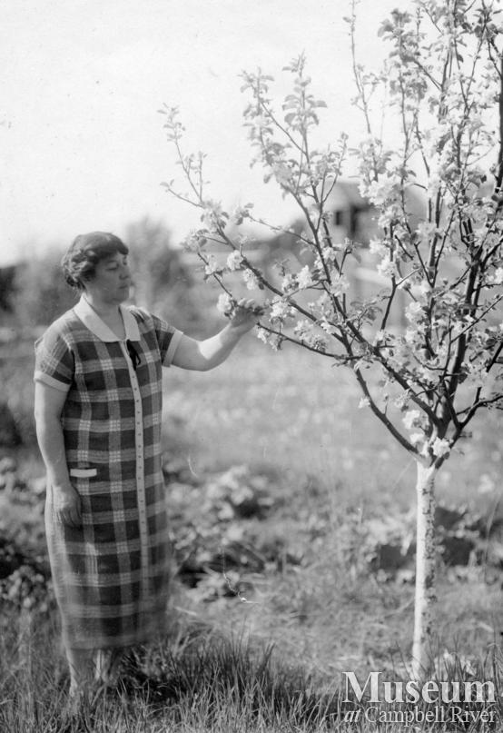 Agnes Twidle admiring blossoms on a tree in her garden at Granite Bay